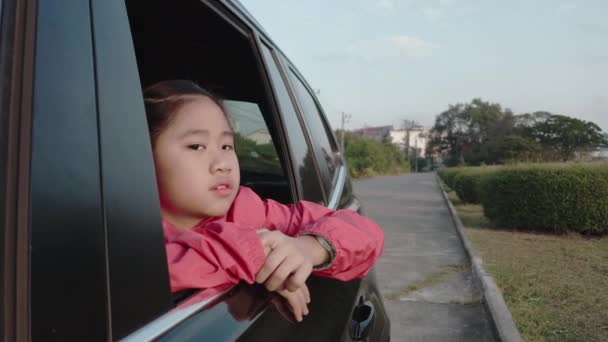 4K亚洲小女孩看着外面的车 女孩在去学校的路上 正在车窗外面看什么东西 孩子们从车上看街景放松一下 — 图库视频影像