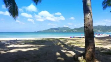 4K kamera, yaz mevsiminde bambu ve beyaz kumaş temasının bir kısmını sahile taşıyor. Kamera hareketleri plaj doğası mavi gökyüzü ve berrak su denizi. Tropikal yaz tatili konsepti