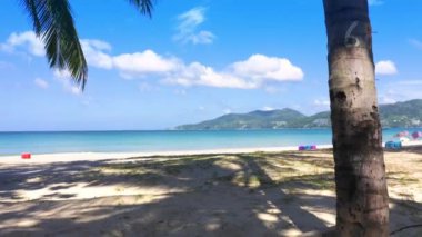 4K kamera, yaz zamanı bambu ve beyaz kumaş temalı bir parçayı sahile taşıyor. Kamera hareketleri plaj doğası mavi gökyüzü ve berrak su denizi. Tropikal yaz tatili konsepti