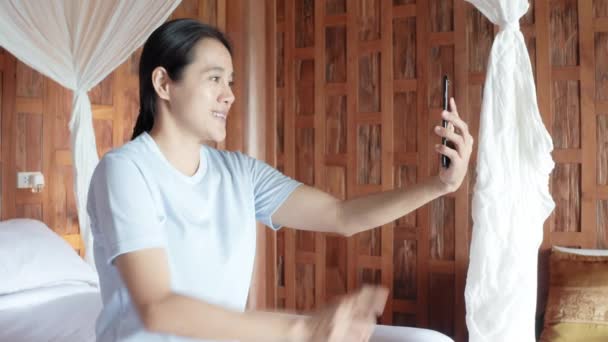 아시아웃는 여성들 방에서 온라인 전화로 스마트폰을 사용하고 호텔에서 비디오 채팅을 — 비디오