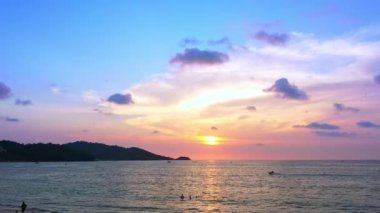 Günbatımı gökyüzü ile güzel tropikal plaj. Güzel Phuket plajı, Andaman Denizi yaz konseptinde ünlü bir turizm merkezidir. Denizin üzerinde günbatımı olan gerçek bir drone manzaralı tropikal plaj