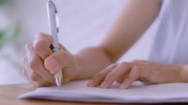 Kapalı kapılar ardında kadınlar kalem kâğıdı kullanır. Kadın eli, beyaz bir çarşafta mavi bir kalemle yazıyı kapatıyor. Kadın bir kağıt parçasına bilgi yazıyor..