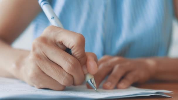 ビジネスの女性の手を閉じるには ペンの文書紙を使用します 白いシートに青いペンで書く女性の手を閉じます 女性は紙に情報を書きます — ストック動画