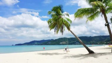 4K Phuket, Tayland. Plaj cenneti ve beyaz gömlekli kız. Kadınlar salıncakta sallanır, hindistan cevizi palmiyesinin altında, güzel tropik sahilde, beyaz kumsalda..