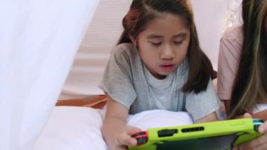 4K Kid, yatak çarşafı çadırında birlikte portatif oyun oynuyor. İki kız kardeş mutlu bir şekilde eğleniyor ve birlikte oyun oynuyorlar. Kardeş kız evdeki çarşaf çadırında oyun oynuyor.