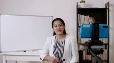 4K Asyalı kadın öğretmen ya da öğretmen evde online öğretmenlik yapıyor. Coronavirus karantinası sırasındaki Covid-19 yeni normal yaşam tarzı. Çevrimiçi uzaktan çalışma