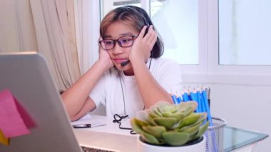 Ev konseptinden 4K öğren. Asyalı kız öğrenciler covid-19 salgınından dolayı internetten sanal internet dersleri alıyorlar. Kız öğrenci evde dizüstü bilgisayarla öğreniyor.