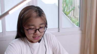 Ev konseptinden 4K öğren. Asyalı kız öğrenciler covid-19 salgınından dolayı internetten sanal internet dersleri alıyorlar. Kız öğrenci evde dizüstü bilgisayarla öğreniyor.