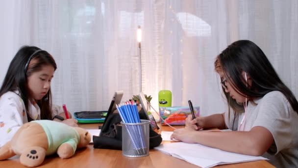 4K名亚洲儿童在家中使用数码平板电脑进行远程学习 在家学习 在同居期间与他人保持距离 坐在桌旁的兄弟姐妹在家上网学习平板电脑 — 图库视频影像