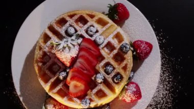 4K. Pasta şefinin eli taze pişmiş waffle 'ların üzerine yabanmersini ve ahududu koyar. Fırından taze ahududu ve böğürtlen ile süslenmiş..