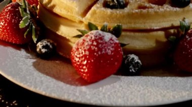 4K. Pasta şefinin eli taze pişmiş waffle 'ların üzerine yabanmersini ve ahududu koyar. Fırından taze ahududu ve böğürtlen ile süslenmiş..