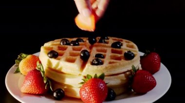 4K. Pasta şefinin eli taze pişmiş waffle 'ların üzerine yabanmersini ve ahududu koyar. Fırından taze ahududu ve böğürtlen ile süslenmiş..