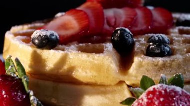 4K. Pasta şefinin eli taze pişmiş waffle 'ların üzerine yabanmersini ve ahududu koyar. Fırından taze ahududu ve böğürtlen ile süslenmiş..