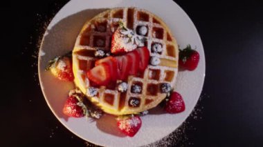 4K. Pasta şefinin eli taze pişmiş waffle 'ların üzerine yabanmersini ve ahududu koyar. Fırından taze ahududu ve böğürtlen ile süslenmiş..