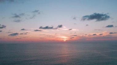 Sakin denizin üzerinde bulutlu arka planda güzel bir günbatımı. Tropik sahilde gün batımı. Doğal yaz konsepti. Sarı ışıkla deniz aşırı güneşin batışı deniz suyunu yansıtır. Huzurlu deniz manzarası. 