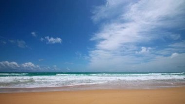 4K Mavi gökyüzü ve bulutları olan güzel tropikal plaj. Dalgaların boş plajı vurduğu tropik bir sahil. Andaman Phuket plajı Tayland. Güzel yaz gününde deniz kumu ve gökyüzü. Tatil özgürlüğü.