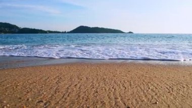 4K Mavi gökyüzü ve bulutları olan güzel tropikal plaj. Dalgaların boş plajı vurduğu tropik bir sahil. Andaman Phuket plajı Tayland. Güzel yaz gününde deniz kumu ve gökyüzü. Tatil özgürlüğü.