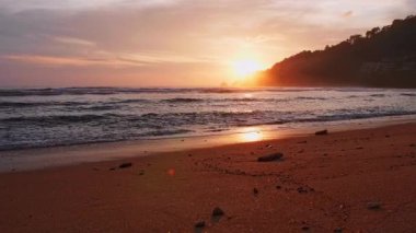 4K Günbatımı gökyüzü ile güzel tropikal plaj. Güzel Phuket plajı, Andaman Denizi yaz konseptinde ünlü bir turizm merkezidir. Denizin üzerinde günbatımı olan gerçek bir drone manzaralı tropikal plaj