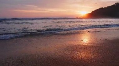 4K Günbatımı gökyüzü ile güzel tropikal plaj. Güzel Phuket plajı, Andaman Denizi yaz konseptinde ünlü bir turizm merkezidir. Denizin üzerinde günbatımı olan gerçek bir drone manzaralı tropikal plaj