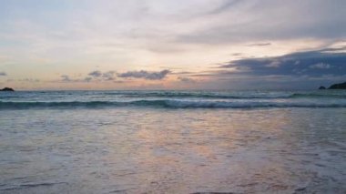 4K Günbatımı gökyüzü ile güzel tropikal plaj. Güzel Phuket plajı, Andaman Denizi yaz konseptinde ünlü bir turizm merkezidir. Denizin üzerinde günbatımı olan gerçek bir drone manzaralı tropikal plaj
