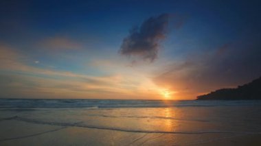 4K Mavi gökyüzü ve bulutları olan güzel tropikal plaj. Dalgaların boş plajı vurduğu tropik bir sahil. Andaman Phuket plajı Tayland. Güzel yaz gününde deniz kumu ve gökyüzü. Tatil özgürlüğü.