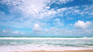 4K Mavi gökyüzü ve bulutları olan güzel tropikal plaj. Dalgaların boş plajı vurduğu tropik bir sahil. Andaman Phuket plajı Tayland. Güzel yaz gününde deniz kumu ve gökyüzü. Tatil özgürlüğü.
