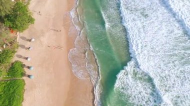 4K Aerial insansız hava aracı, Phuket, Tayland 'da günbatımı olan tropikal plajdaki insanların en iyi görüntüsü Andaman Denizi' nde ünlü bir turizm merkezidir. Sahilde oynayan mutlu insanlar.