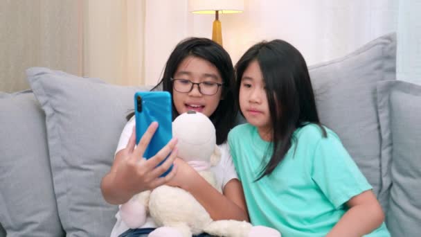 快乐的兄弟姐妹孩子们坐在客厅的沙发上和父母一起用手机聊天 微笑的姐姐用智能手机给可爱的妹妹打电话 和家人聊天 生活方式 — 图库视频影像