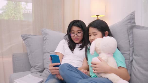 快乐的兄弟姐妹孩子们坐在客厅的沙发上和父母一起用手机聊天 微笑的姐姐用智能手机给可爱的妹妹打电话和家人聊天 — 图库视频影像