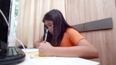Ev konseptinden 4K öğren. Asyalı kız öğrenciler covid-19 salgınından dolayı internetten sanal internet dersleri alıyorlar. Kız öğrenci evde dizüstü bilgisayarla öğreniyor.