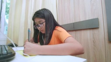 Ev konseptinden 4K öğren. Asyalı kız öğrenciler covid-19 salgınından dolayı internetten sanal internet dersleri alıyorlar. Kız öğrenci evde dizüstü bilgisayarla öğreniyor.