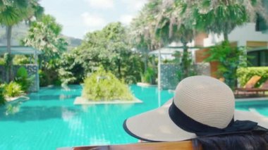 Şapkalı gezgin kadın lüks otel tropik yüzme havuzunda tatilini rahatlatıyor. Yaz kaplıcalarının tadını çıkarıyorum. Plaj turizmi, okyanus hayatı, açık hava.