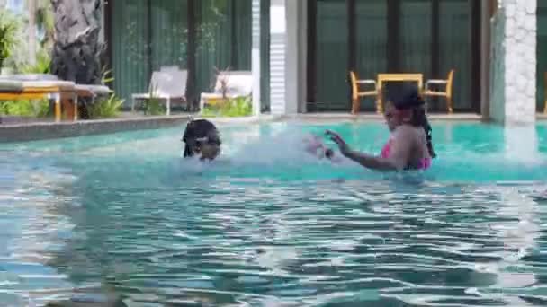 幸せな家族の子供たちはホテルで夏休みの時間にスイミングプールで泳いだりダイビングしたりします ホテルの休日にプールで幸せな運動をしている子供たち — ストック動画