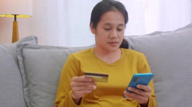 Kredi kartı tutan ve cep telefonu kullanan bir kadın. Evde çalışan kadınlar. Çevrimiçi alışveriş, e-ticaret, internet bankacılığı, harçlık, ev konseptiyle çalışmak. Çevrimiçi teknoloji alışverişi kavramı