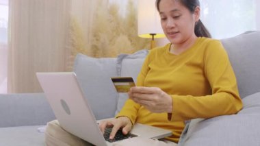 Kredi kartı tutan ve cep telefonu kullanan bir kadın. Evde çalışan kadınlar. Çevrimiçi alışveriş, e-ticaret, internet bankacılığı, harçlık, ev konseptiyle çalışmak. Çevrimiçi teknoloji alışverişi kavramı