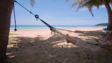 Phuket Tayland. Gün batımında sahilde hamak üzerine kitap yazan Asyalı genç bir kadın. Genç ve çekici bir kadın hamakta sallanıyor. Yaz tatili