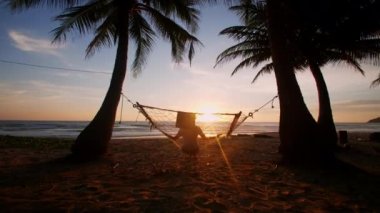 Phuket Tayland. Gün batımında hamakta dinlenen Asyalı genç bir kadın. Genç ve çekici bir kadın hamakta sallanıyor. Yaz tatili