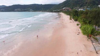 4K Aerial insansız hava aracı, Phuket, Tayland 'da günbatımı olan tropikal plajdaki insanların en iyi görüntüsü Andaman Denizi' nde ünlü bir turizm merkezidir. Sahilde oynayan mutlu insanlar.
