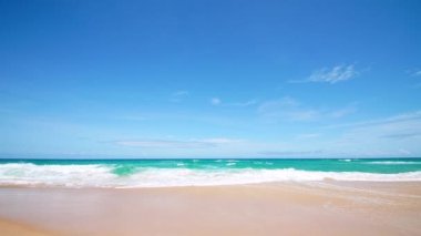 4K Mavi gökyüzü ve bulutları olan güzel tropikal plaj. Dalgaların boş plajı vurduğu tropik bir sahil. Andaman Phuket plajı Tayland. Güzel yaz gününde deniz kumu ve gökyüzü. Tatil özgürlüğü.