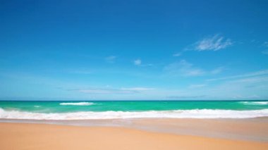 4K Mavi gökyüzü ve bulutları olan güzel tropikal plaj. Dalgaların boş plajı vurduğu tropik bir sahil. Andaman Phuket plajı Tayland. Güzel yaz gününde deniz kumu ve gökyüzü. Tatil özgürlüğü.