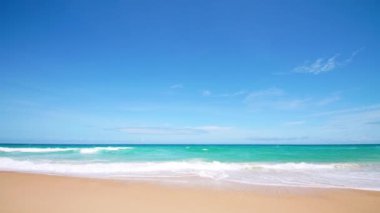 4K Mavi gökyüzü ve bulutları olan güzel tropikal plaj. Dalgaların boş plajı vurduğu tropik bir sahil. Andaman Phuket plajı Tayland. Güzel yaz gününde deniz kumu ve gökyüzü. Tatil özgürlüğü.