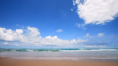 4K Mavi gökyüzü ve bulutları olan güzel tropikal plaj. Dalgaların boş plajı vurduğu tropik bir sahil. Andaman Phuket plajı Tayland. Güzel yaz gününde deniz kumu ve gökyüzü. Tatil özgürlüğü.