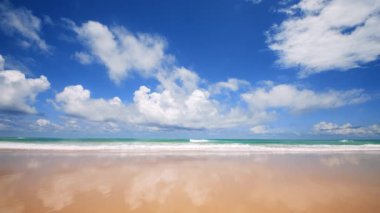 4K Mavi gökyüzü ve bulutları olan güzel tropikal plaj. Dalgaların boş plajı vurduğu tropik bir sahil. Andaman Phuket plajı Tayland. Güzel yaz gününde deniz kumu ve gökyüzü. Tatil özgürlüğü.