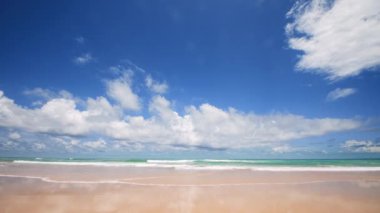 4K Mavi gökyüzü ve bulutları olan güzel tropikal plaj. Dalgaların boş plajı vurduğu tropik bir sahil. Andaman Phuket plajı Tayland. Güzel yaz gününde deniz kumu ve gökyüzü. Tatil özgürlüğü.