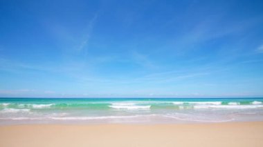 4K Mavi gökyüzü ve bulutları olan güzel tropikal plaj. Dalgaların boş plajı vurduğu tropik bir sahil. Andaman Phuket plajı Tayland. Güzel yaz gününde deniz kumu ve gökyüzü. Tatil özgürlüğü.