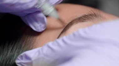 Mikropatenli kaş dövmesini kapat. Eldivenli güzellik uzmanı genç bir kadına kaş şeklini kalıcı olarak düzeltiyor. Güzellik salonunda kaş dövmesi..
