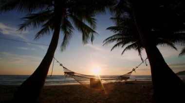 Phuket Tayland. Gün batımında hamakta dinlenen Asyalı genç bir kadın. Genç ve çekici bir kadın hamakta sallanıyor. Yaz tatili