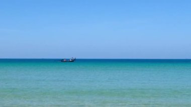 4K Mavi gökyüzü ve bulutları olan güzel tropikal plaj. Dalgaların boş plajı vurduğu tropik bir sahil. Andaman Phuket plajı Tayland. Güzel yaz gününde deniz kumu ve gökyüzü. Tatil özgürlüğü.