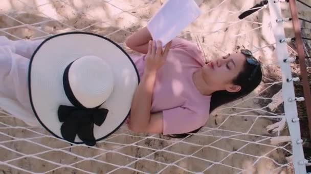 Phuket泰国 日落时分 亚洲年轻女子在海滩边的吊床上看书 放松身心 年轻迷人的女性在吊床上荡秋千 暑假假期 — 图库视频影像