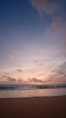 Dikey görüntü. 4K Günbatımı gökyüzü ile güzel tropikal plaj. Güzel Phuket plajı, Andaman Denizi yaz konseptinde ünlü bir turizm merkezidir. Günbatımlı tropik plaj manzaralı gerçek bir drone.